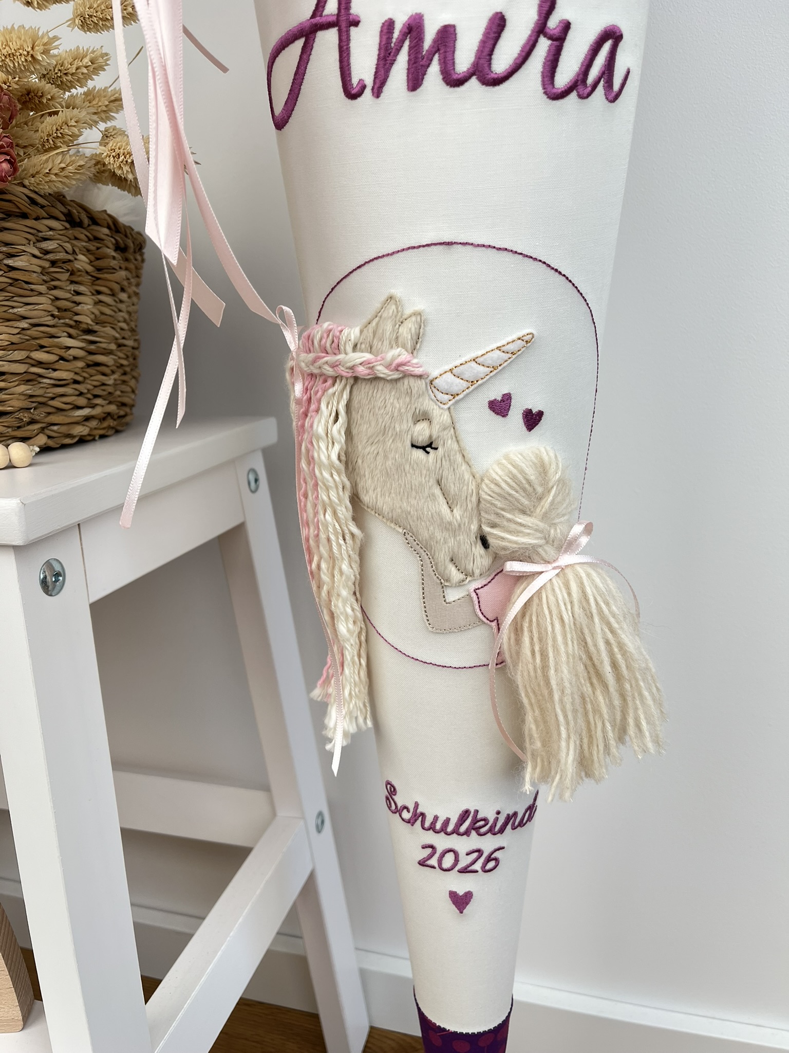 Detailansicht Einhorn mit Wollmähne und Mädchen mit Wollzopf auf cremeweißer Schultüte mit Name und Schulkind-Schriftzug