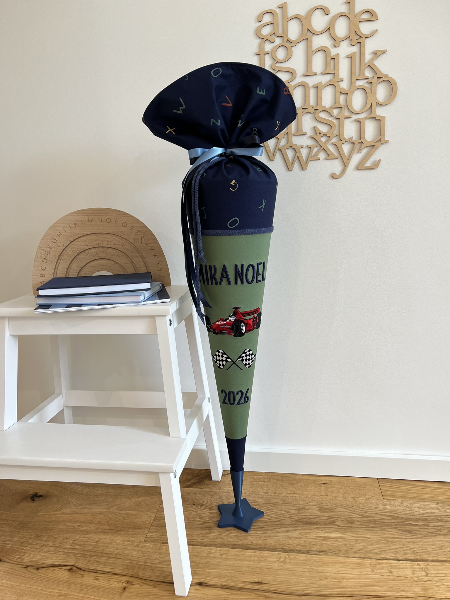 Schultüte Formel 1 in Grün und Marineblau mit Buchstabenstoff, gesticktem Rennwagen und Zielflaggen, Gesamtansicht mit Ständer